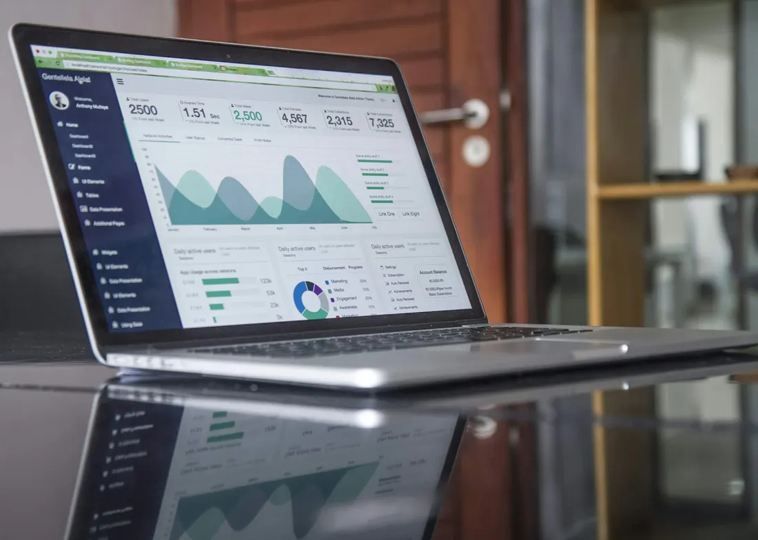 Laptop showing a sales analytics dashboard on a reflective desk